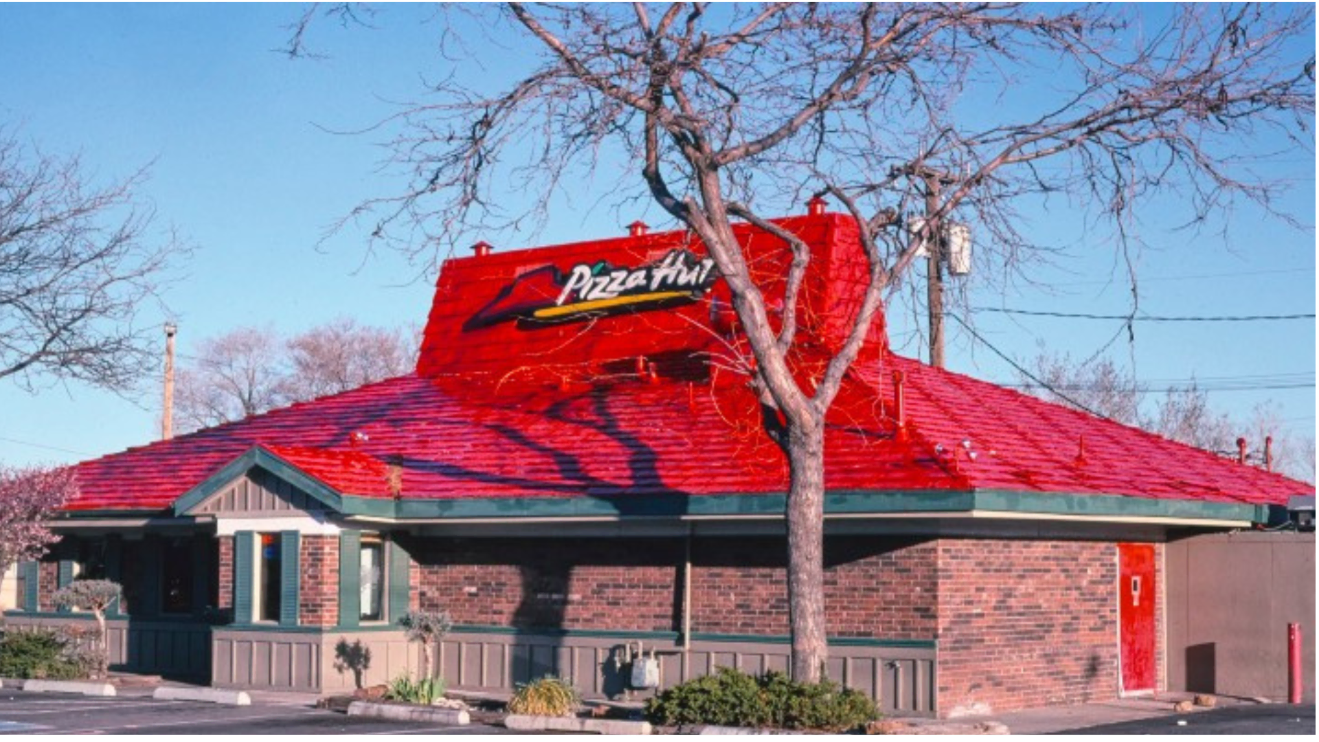 pizza hut exterior with red tiled roof and tree shadows