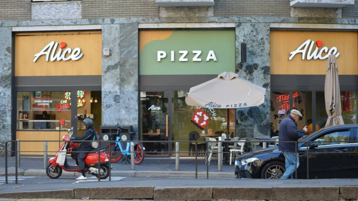 alice pizza: facciata urbana con scooter rosso