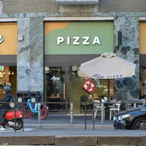 alice pizza: facciata urbana con scooter rosso