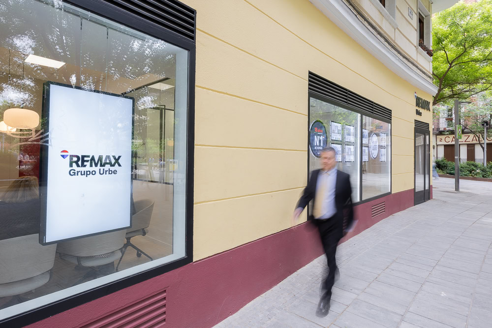 oficina re/max en fachada urbana con escaparate