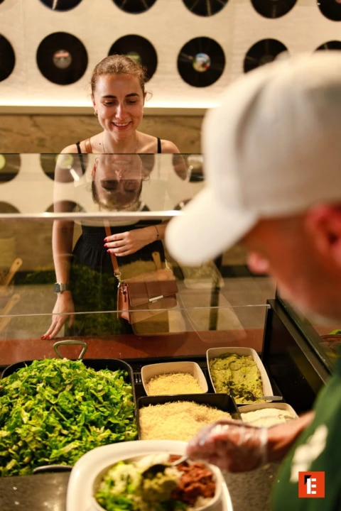 young woman choosing modern salad bowl with guacamole