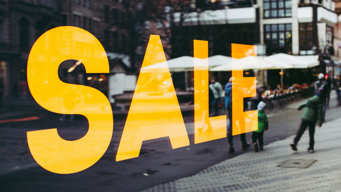 orange sale window reflecting city street scene