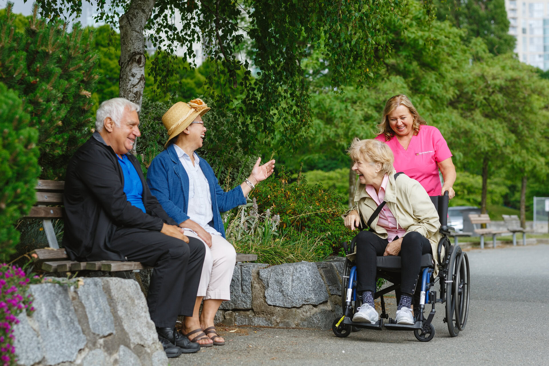seniors laughing in park with caregiver and wheelchair