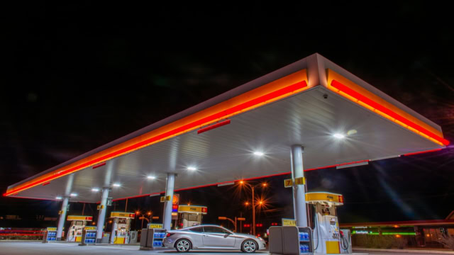 station service de nuit au néon avec voiture