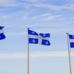 trois drapeaux fleurdelisés sur ciel bleu