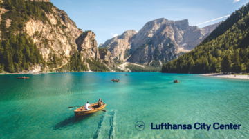 türkisblauer alpensee mit ruderboot und bergen