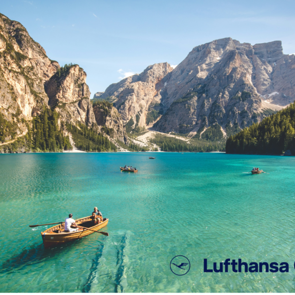 türkisblauer alpensee mit ruderboot und bergen