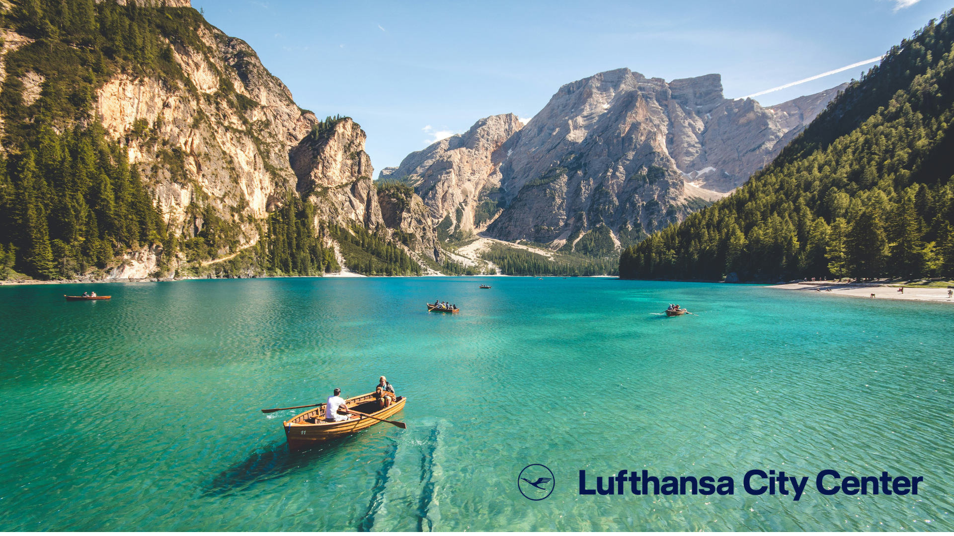 türkisblauer alpensee mit ruderboot und bergen