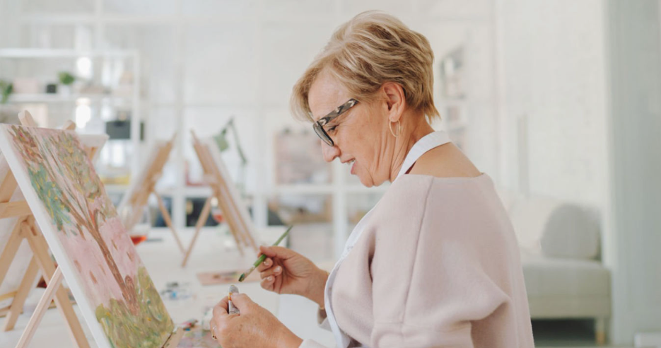 senior artist painting florals in a bright studio