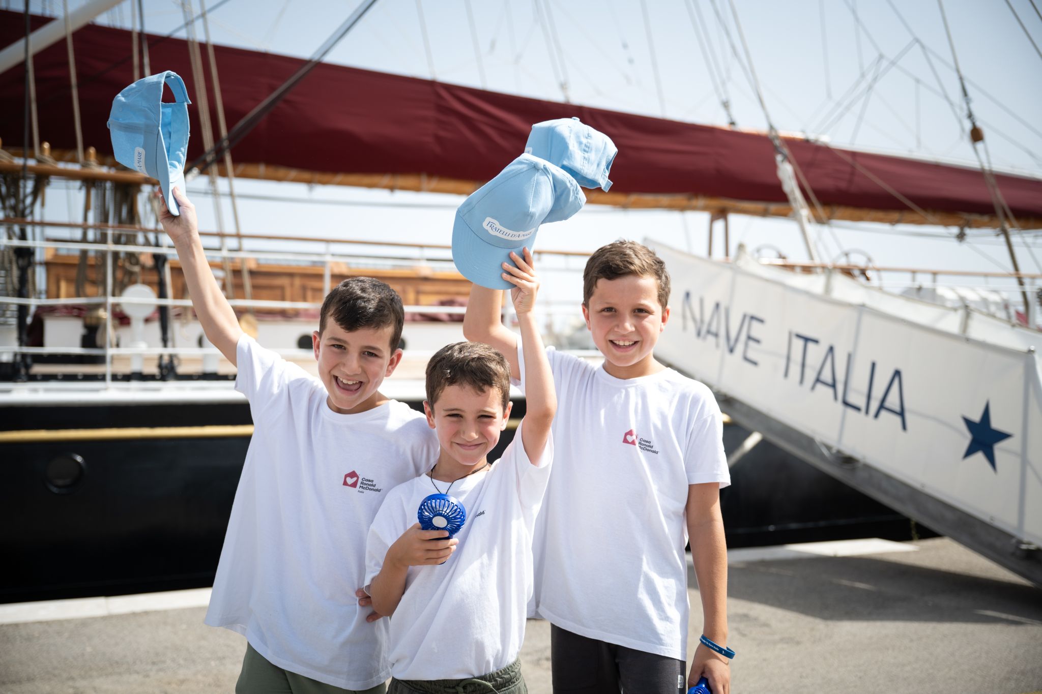 bambini sorridenti sul molo accanto alla nave italia
