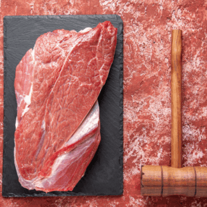 carne cruda sobre pizarra con mazo de carnicero
