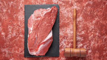 carne cruda sobre pizarra con mazo de carnicero