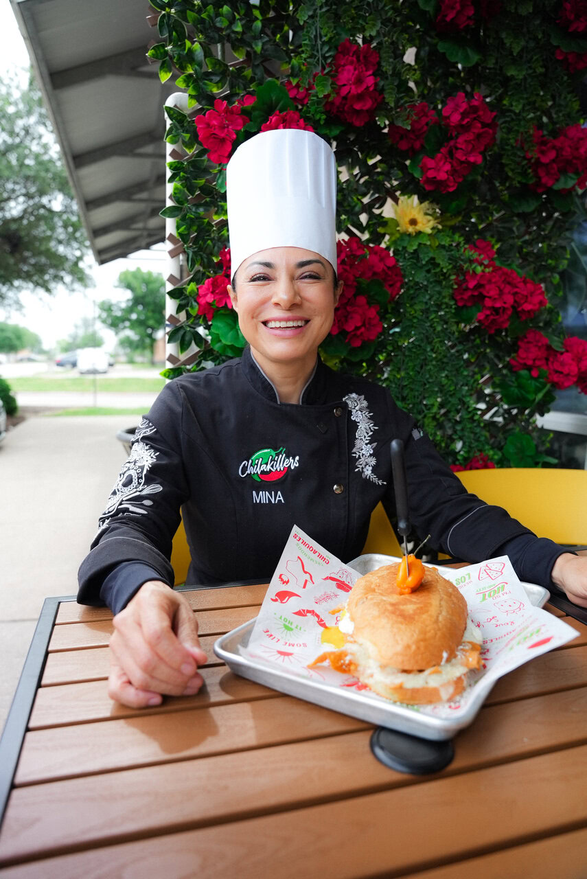 chef mina sonríe con sándwich gourmet al aire libre