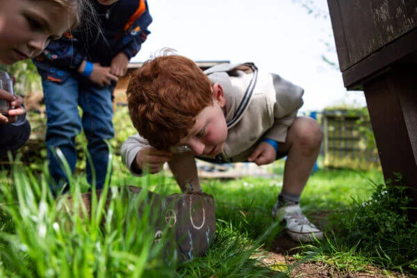 curious children exploring garden with magnifying glass