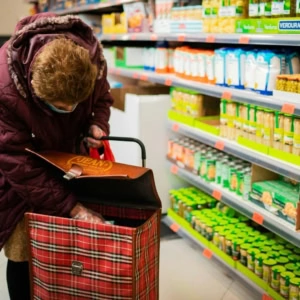 femme Âgée au chariot dans le rayon conserves du supermarché