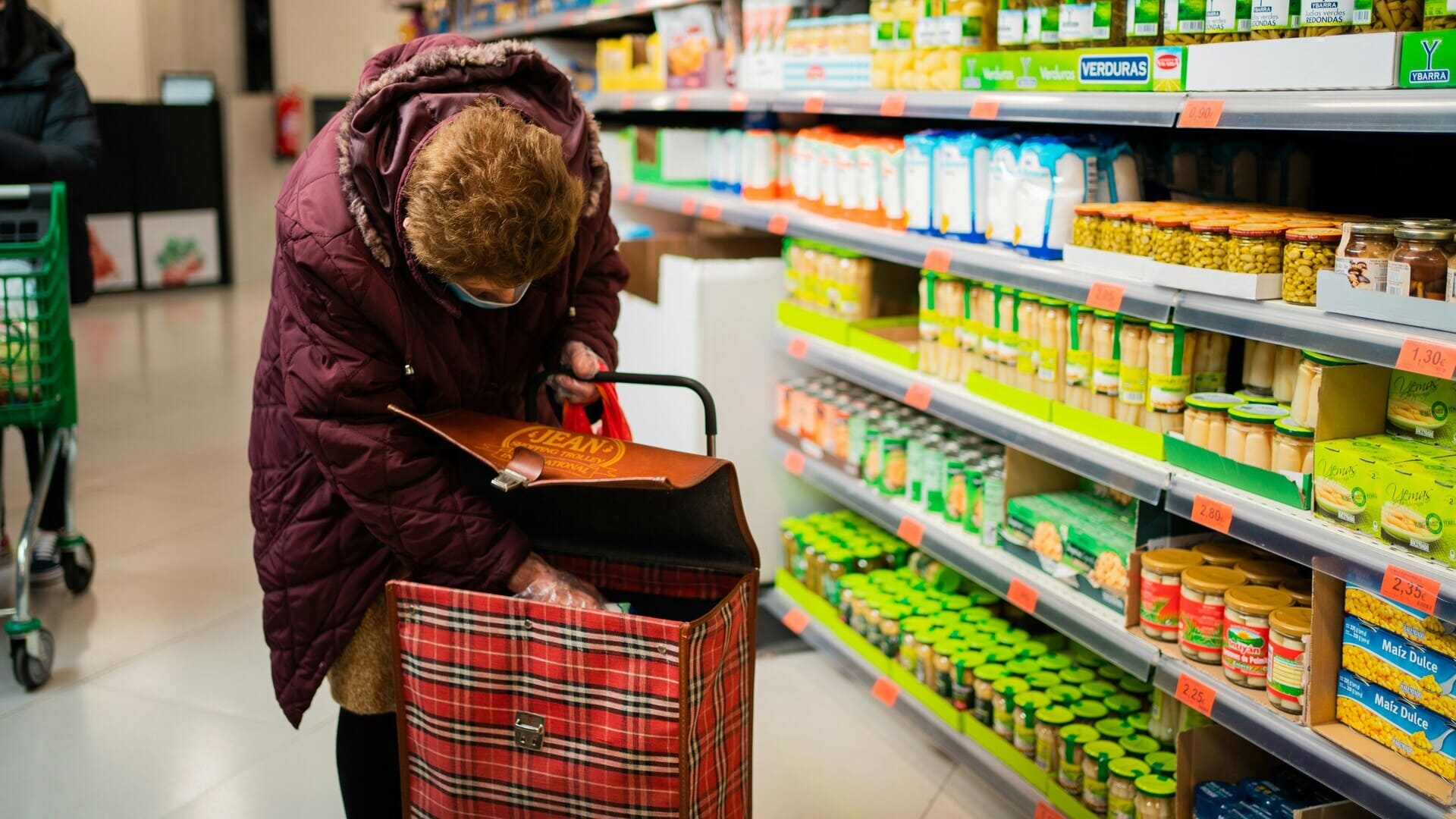 femme Âgée au chariot dans le rayon conserves du supermarché