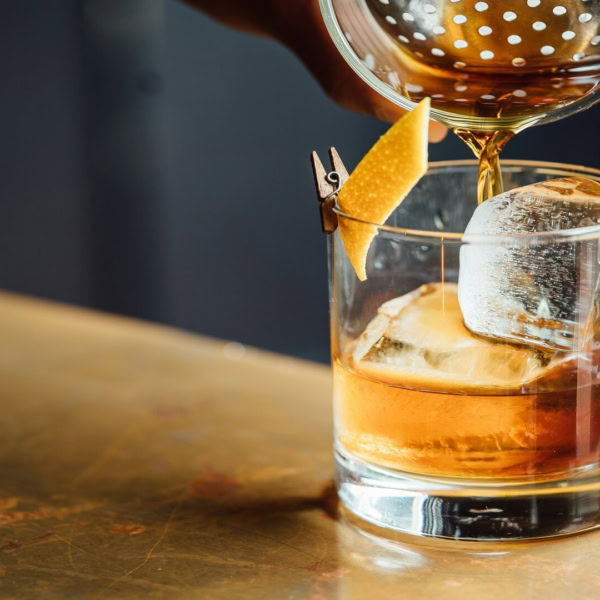 cocktail ambré au glaçon carré et zeste