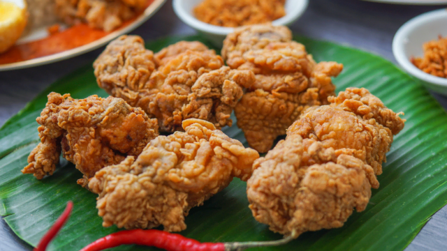 crispy fried chicken on banana leaf with red chilies