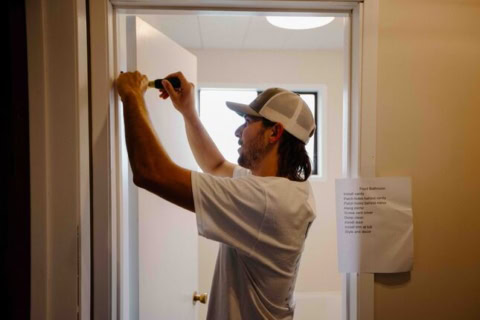 handyman fixing door hinge in doorway