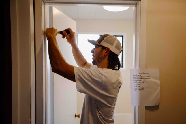 handyman fixing door hinge in doorway