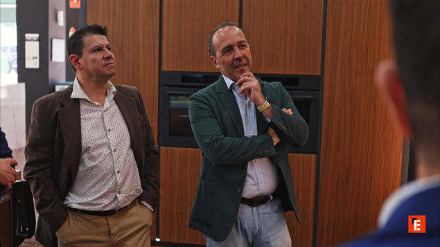 dos hombres observan una cocina moderna en showroom