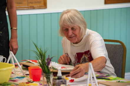 senior woman crafting at community art table