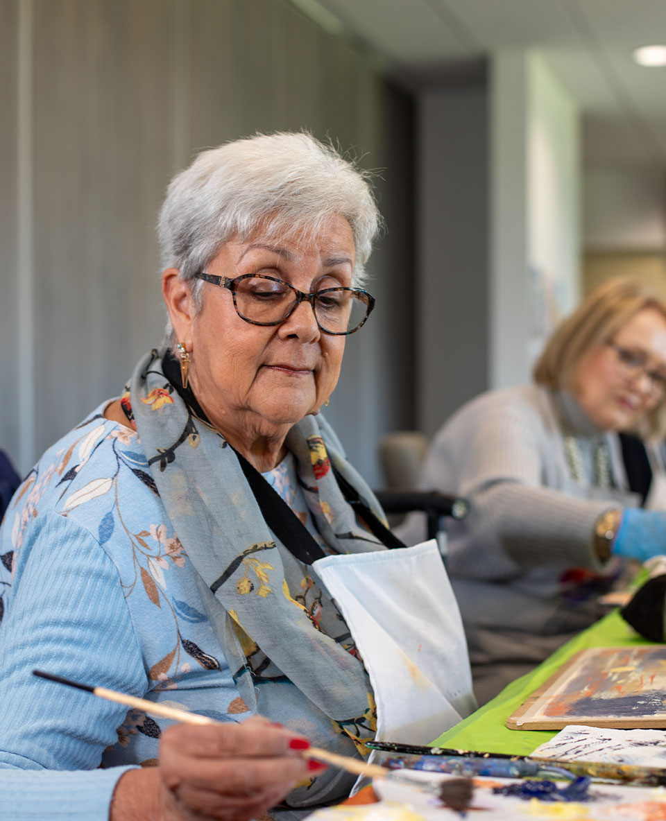 senior woman painting in community art class