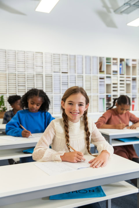 Élève souriante Écrivant en classe lumineuse