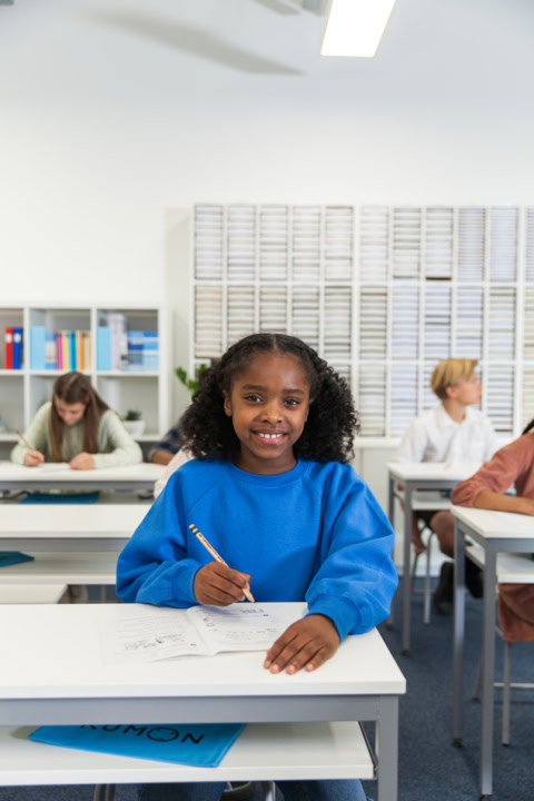 Écolière souriante au pupitre en plein travail