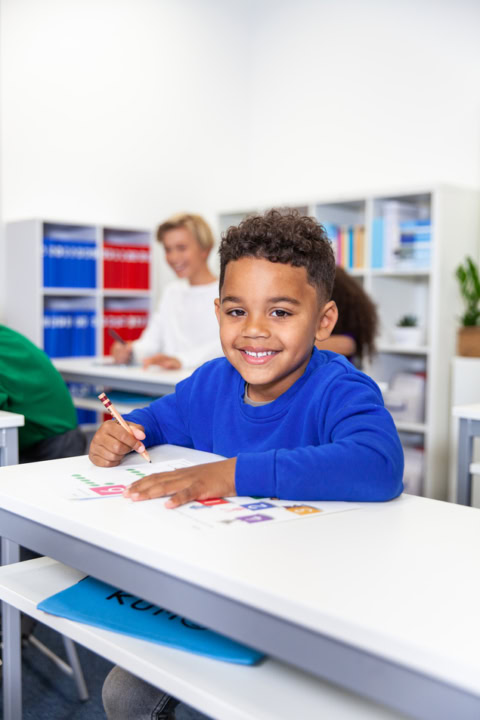 Élève souriant À son bureau en classe