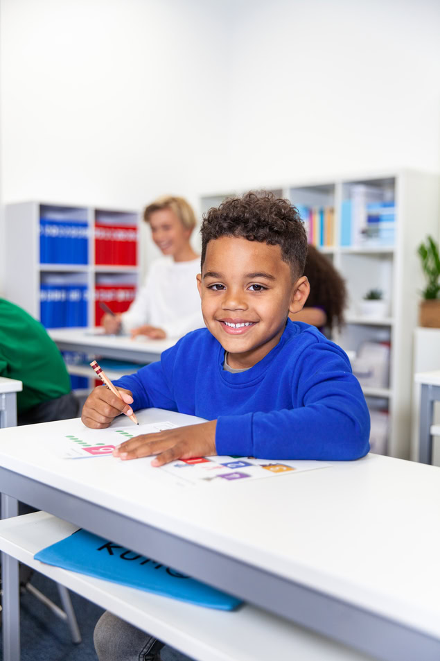 Élève souriant À son bureau en classe
