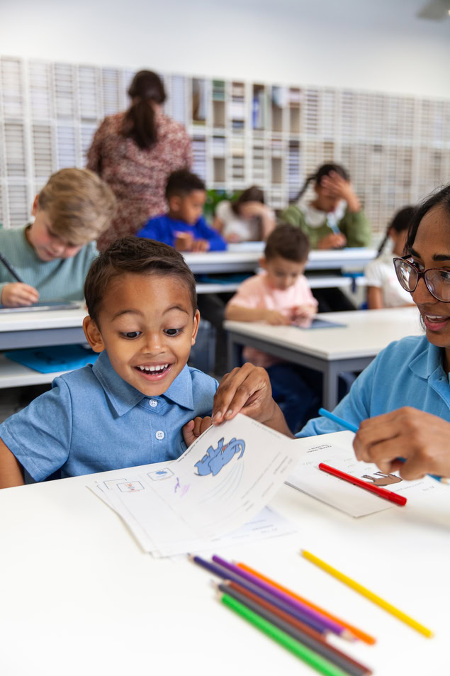 Élève souriant guidé par lenseignant en classe