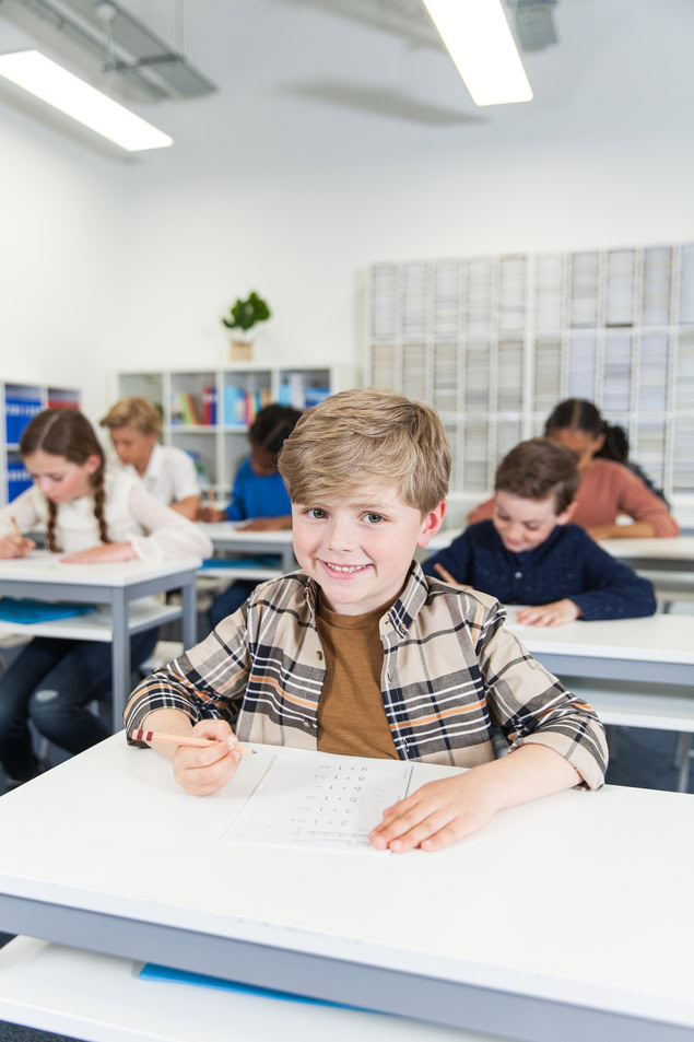 garçon souriant concentré sur sa feuille en classe