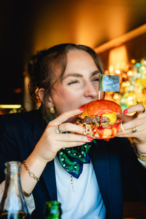 jeune femme croquant un burger gourmet en restaurant