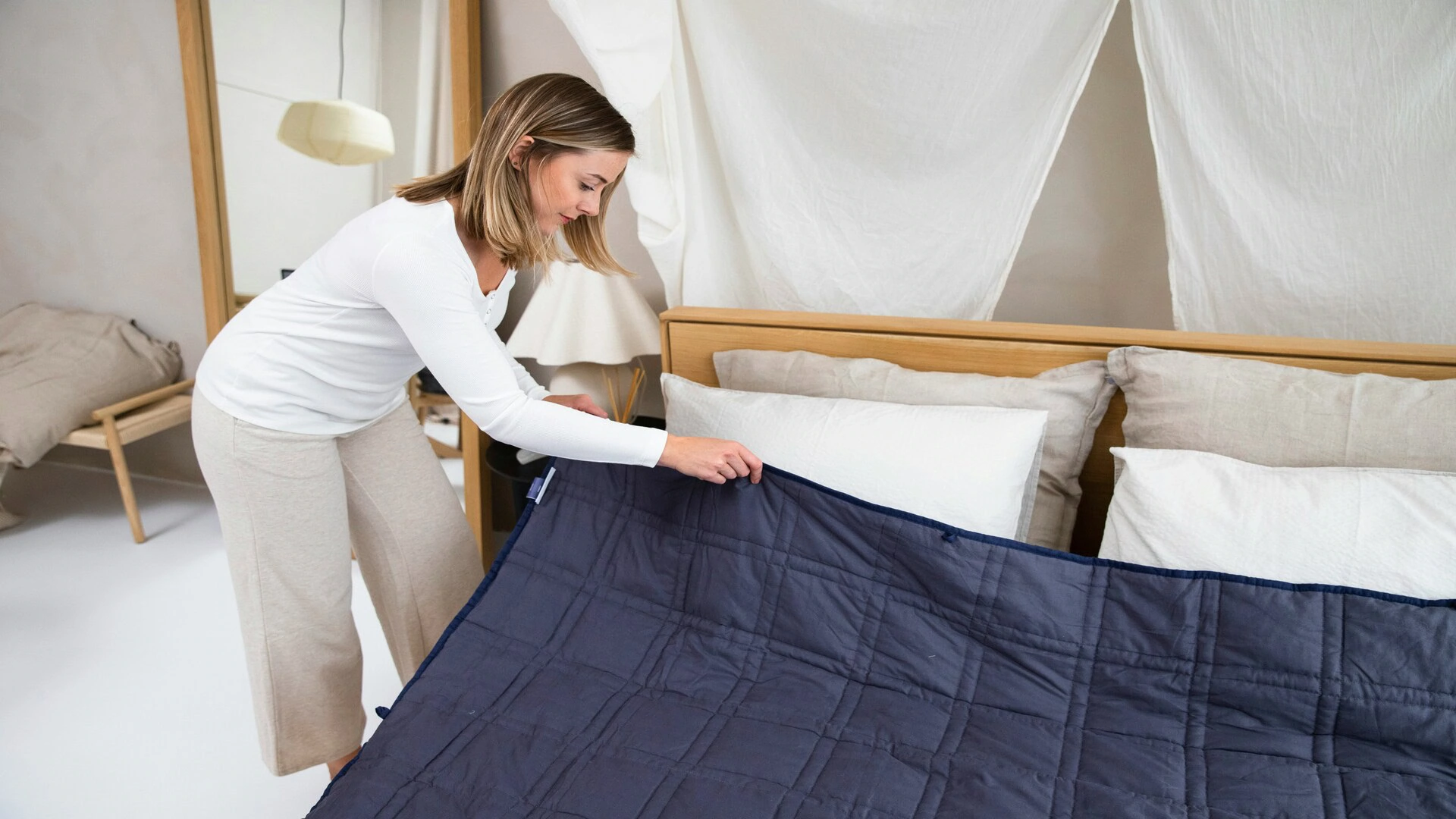 femme range son lit avec couette bleu marine