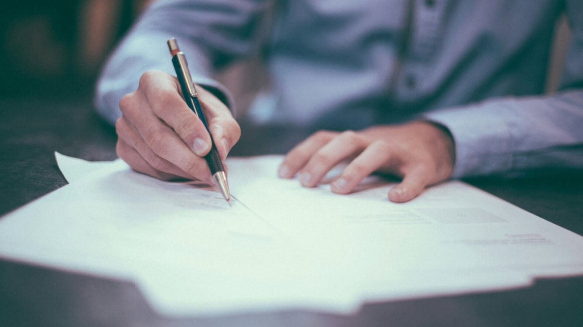 mano che firma un documento con penna