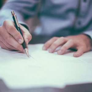 mano che firma un documento con penna