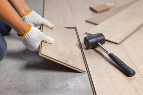 gloved hands installing oak look laminate flooring