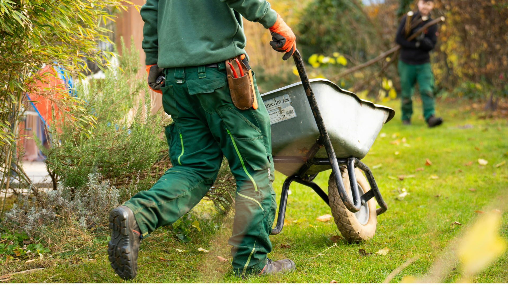 gärtner schiebt schubkarre im garten bei der pflege