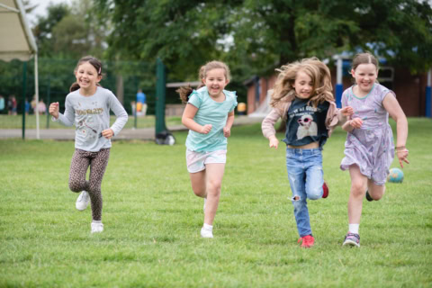 joyful girls running across a green field