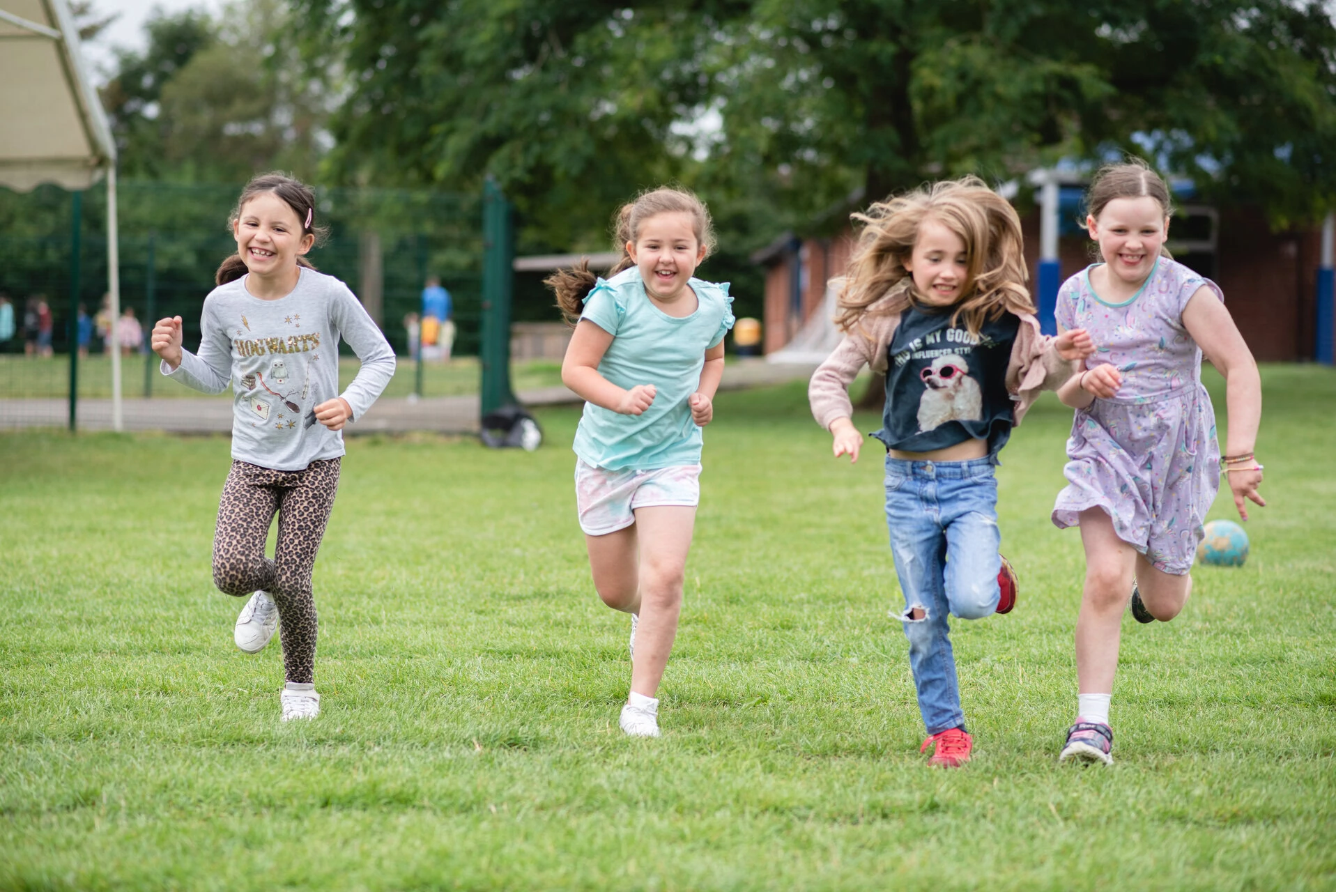 joyful girls running across a green field