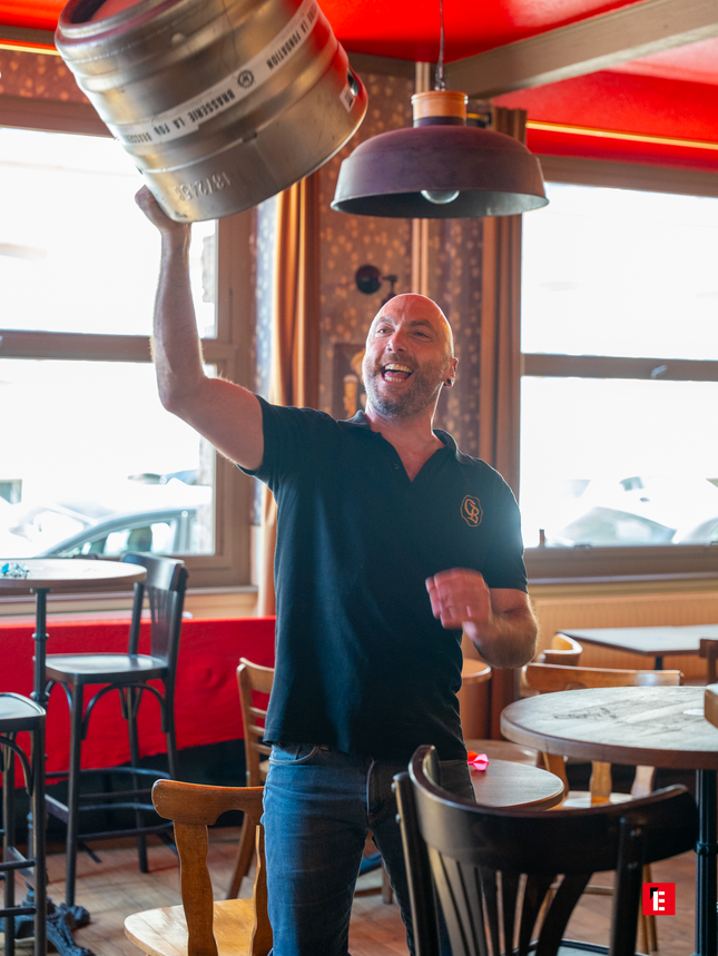 homme souriant brandissant un fût de bière au pub