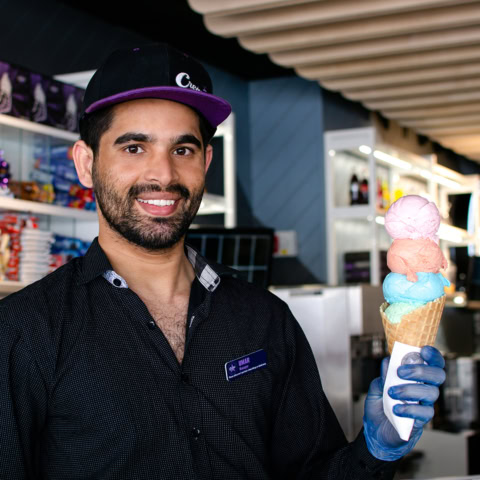smiling server holding four scoop pastel waffle cone