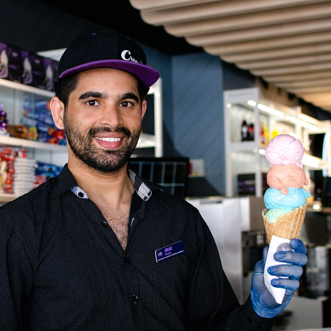 smiling server holding four scoop pastel waffle cone