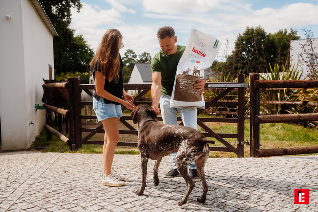 homme et fille donnent des croquettes à un chien