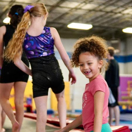 smiling girls practicing gymnastics indoors