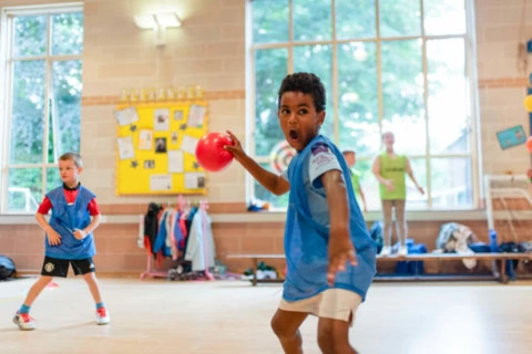 school gym action: child throwing red ball
