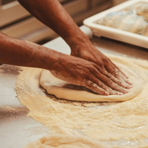 mains pétrissant une pâte à pizza artisanale