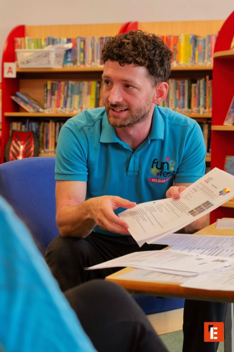 turquoise shirt man discussing papers in library