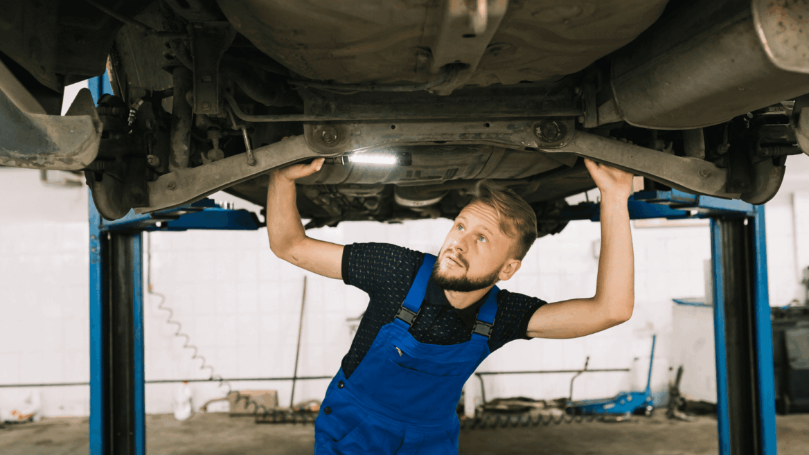 mecánico inspecciona suspensión de coche elevado en taller
